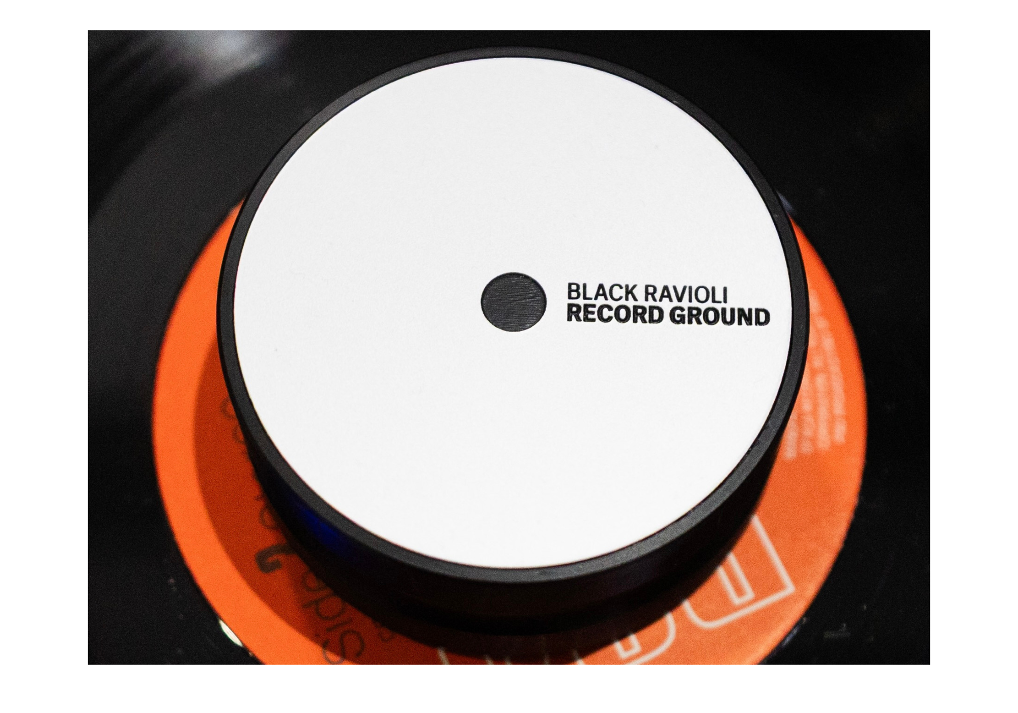 Circular record ground with white top and black rim; label reads BLACK RAVIOLI RECORD GROUND.